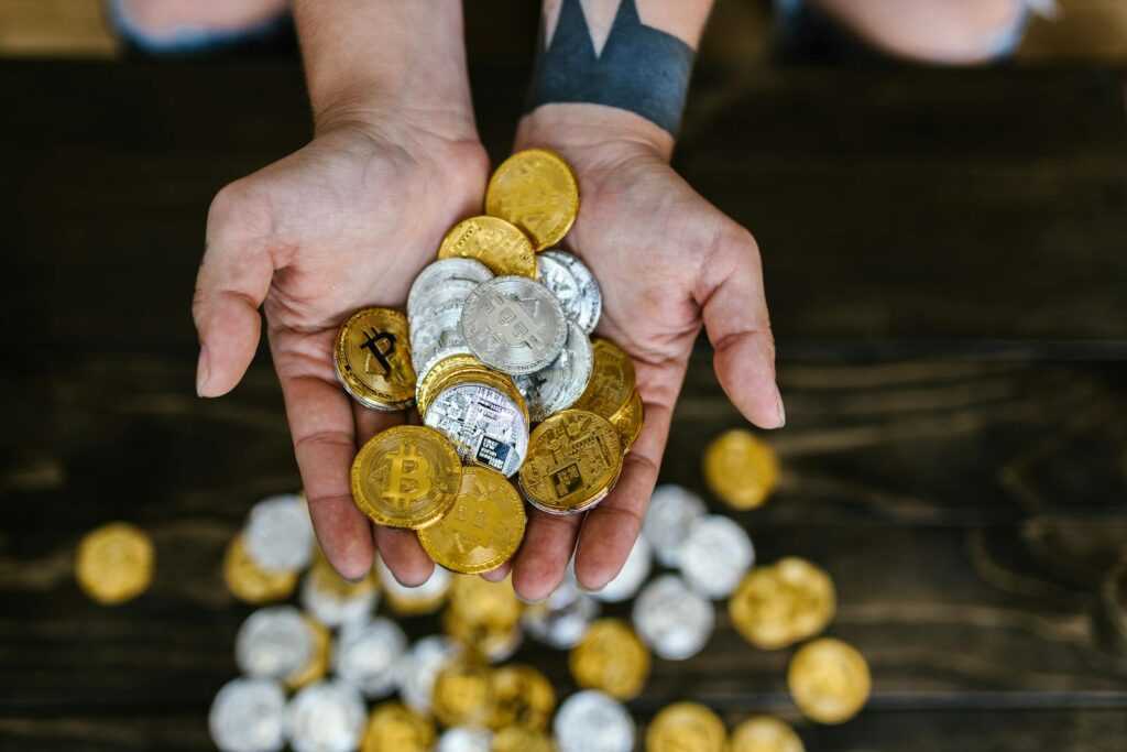 High angle of hands holding gold and silver cryptocurrency coins, symbolizing digital wealth.