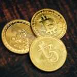 three gold bitcoins sitting on top of a wooden table