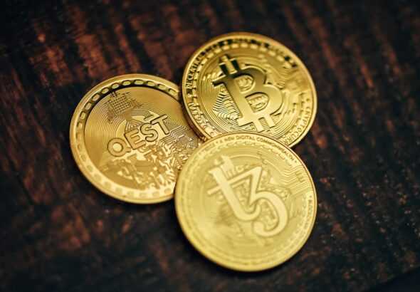 three gold bitcoins sitting on top of a wooden table