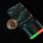 a bitcoin sitting on top of a smart phone