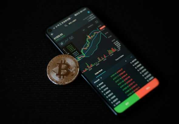 a bitcoin sitting on top of a smart phone