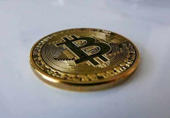 a gold bit coin sitting on top of a white table