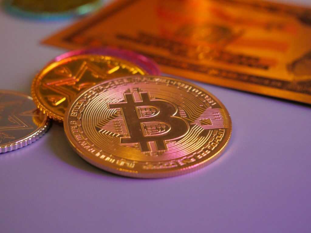 Golden bitcoin coin with other coins and card.
