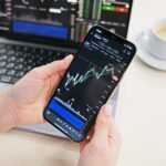 a person holding a cell phone in front of a laptop