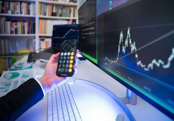 A man holding a remote control in front of a computer
