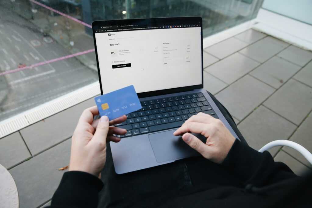 A person sitting in a chair with a laptop and a credit card