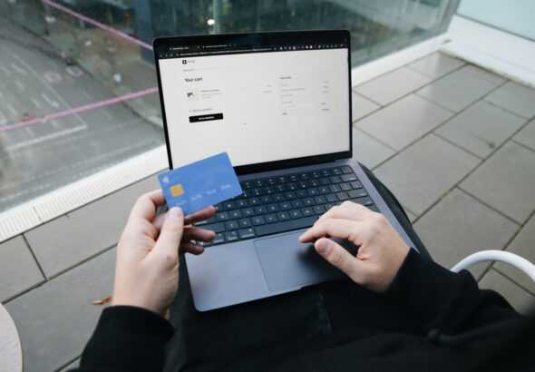 A person sitting in a chair with a laptop and a credit card